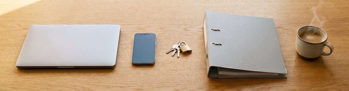 Schreibtisch mit zugeklapptem Laptop, Smartphone, Vorhängeschloss und Aktenordner als Symbol für den Wertgarantie Login