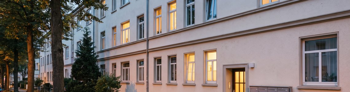 Altbau-Mehrfamilienhaus in einer Wohnstraße in der Abenddämmerung mit Briefkästen am Eingang